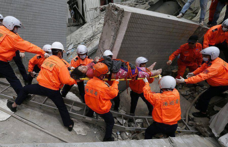 epa05145494 Rescuers carry a survivor from a collapsed building following a 6.4 magnitude earthquake that struck the area in Tainan City, Taiwan, 06 February 2016. At least three people, including an infant, were killed and dozens injured when a high-rise building collapsed after a 6.4-magnitude earthquake struck southern Taiwan early 06 February, authorities said. The 17-storey building in Tainan city was said to be home to about 200 people in 60 households, state-run media reported. Several other buildings in Tainan collapsed or were damaged by the quake that struck at 03:57 am local time (19:57 GMT Friday).  EPA/RITCHIE B. TONGO